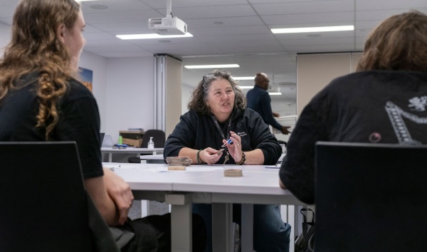 A woman sitting at a table with some other women and shuffling uno cards