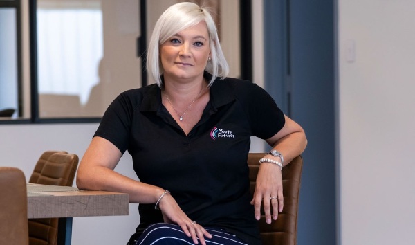 A youth futures worker sitting at a kitchen table and looking into a camera
