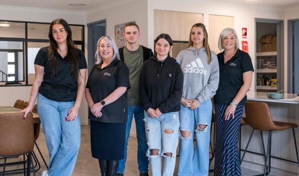 Some youth futures workers standing next to some teenagers in a dining rom