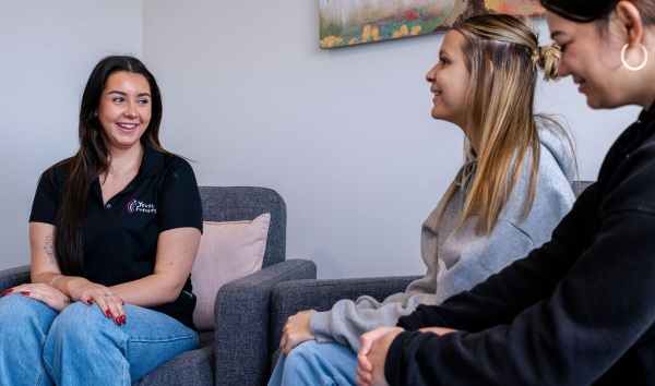 Three teenage girls sitting on couches and smiling as they chat