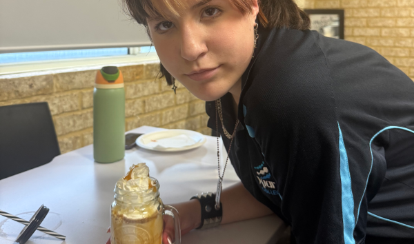 A girl with a dessert in a jar looking into the camera