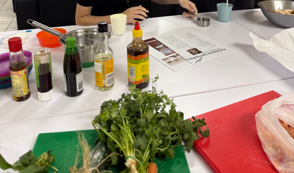 A person looking at a recipe that's sitting next to a bunch of ingredients laid out on a table