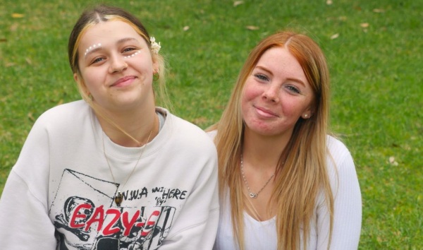 Two girls sitting on grass together