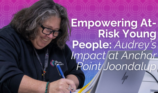 Woman in youth futures hoodie writing in notebook while using laptop