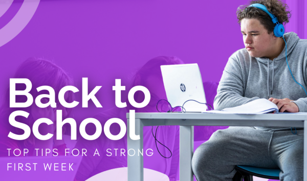 Student sitting at desk listening to something on laptop in front of purple banner