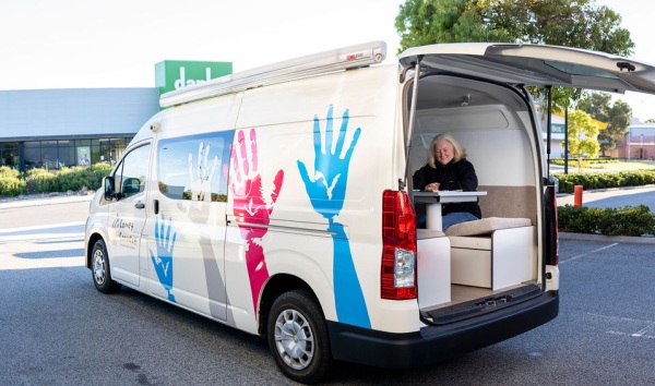 A comet connect van with the logo, colourful hands decorating the side and a woman sitting at a desk inside the van
