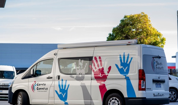 A white van with the comet connect logo and paintings of hands in different colours in a parking lot